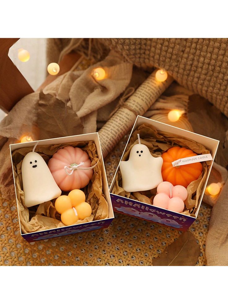 two boxes filled with halloween decorations sitting on top of a table next to candles and pumpkins