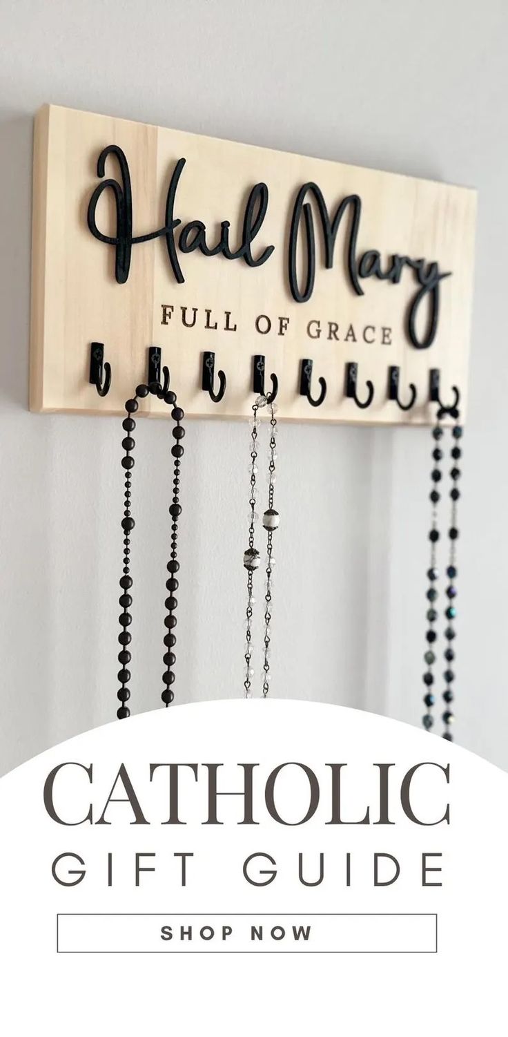 a wooden sign that says catholic gift guide on the wall with beads hanging from it