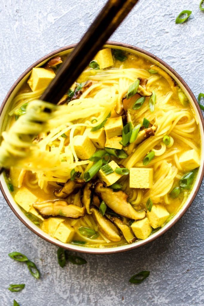 a bowl filled with noodles and chopsticks on top of a gray countertop