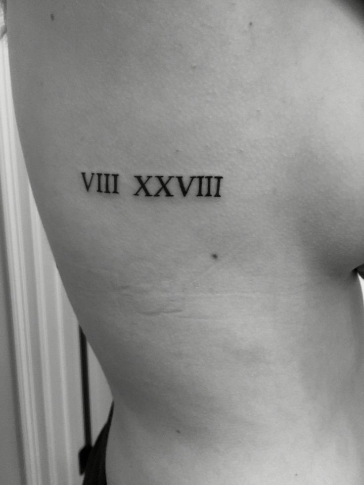 a woman's lower back with roman numerals tattoo on her left side