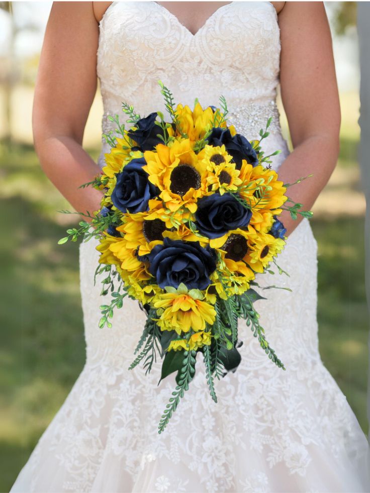 a bride holding a bouquet of sunflowers and blue roses on her wedding day