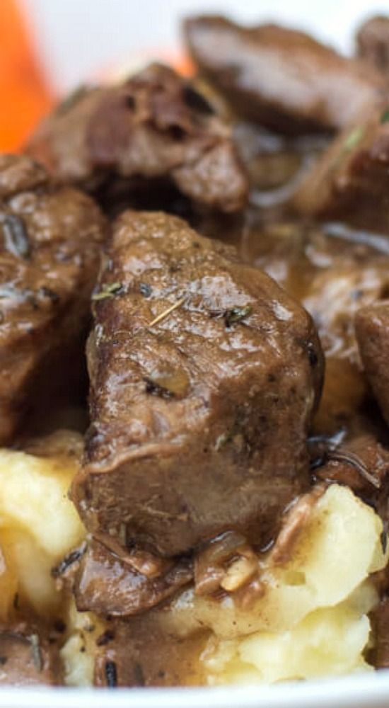 meat and potatoes in gravy on a white plate