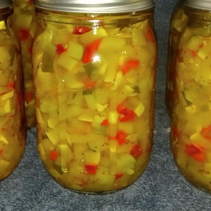 four jars filled with pickles and peppers