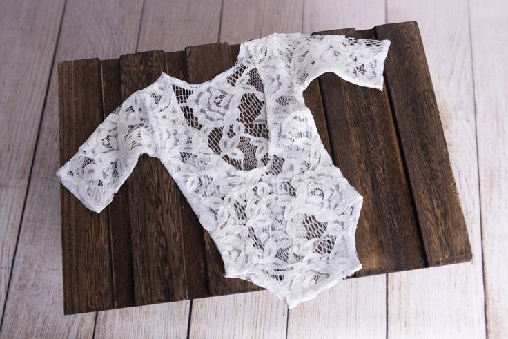 Lovely handmade bodysuit perfect for the vintage look. Made with a lovely floral lace and shaped with an open back to accentuate baby's back. Stretchy enough to fit newborns 0-14 days old. Dress baby up in this white lace bodysuit and style with one of our Smooth or Textured Bean Bag Fabrics OR lay baby in one our Vintage Beds. CARE INSTRUCTIONS: Handwash with baby soap and air or lay flat to dry. Material: lace.Color: white. Approximate measurements: Cuff to cuff: 15 in Neck to bottom: 12 in. C Fitted White Onesie For Baptism, White Fitted Onesie For Baptism, White Stretch Bodysuit With Lace Trim, White Summer Onesie For Baptism, White Onesie For Baptism In Summer, Spring White Bodysuit With Lace Trim, Fitted White Bodysuit With Lace Closure, White Lace Bodysuit For Party, Spring White Lace Trim Bodysuit