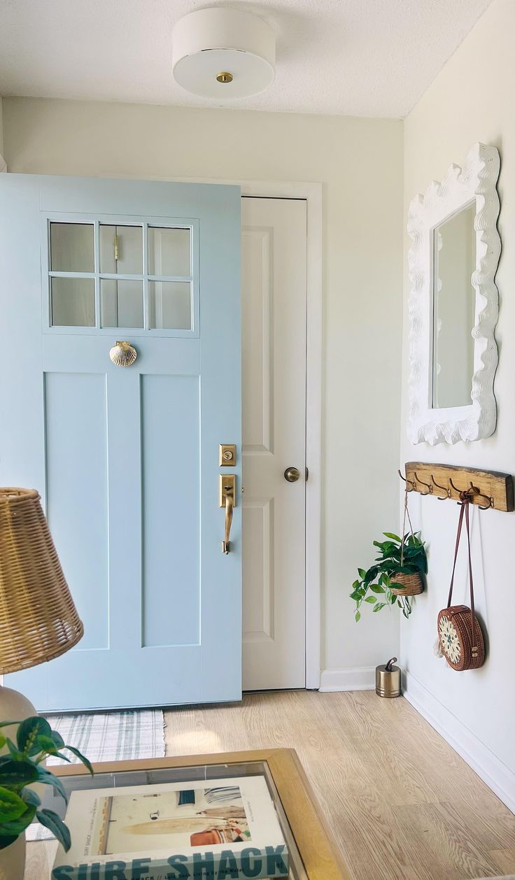 a blue front door and mirror in a white room with wood flooring on the side