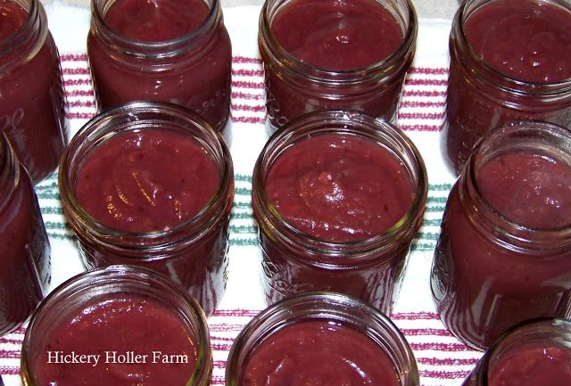 several jars filled with red liquid sitting on top of a white and green table cloth