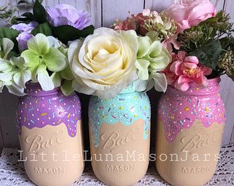 three painted mason jars with flowers in them