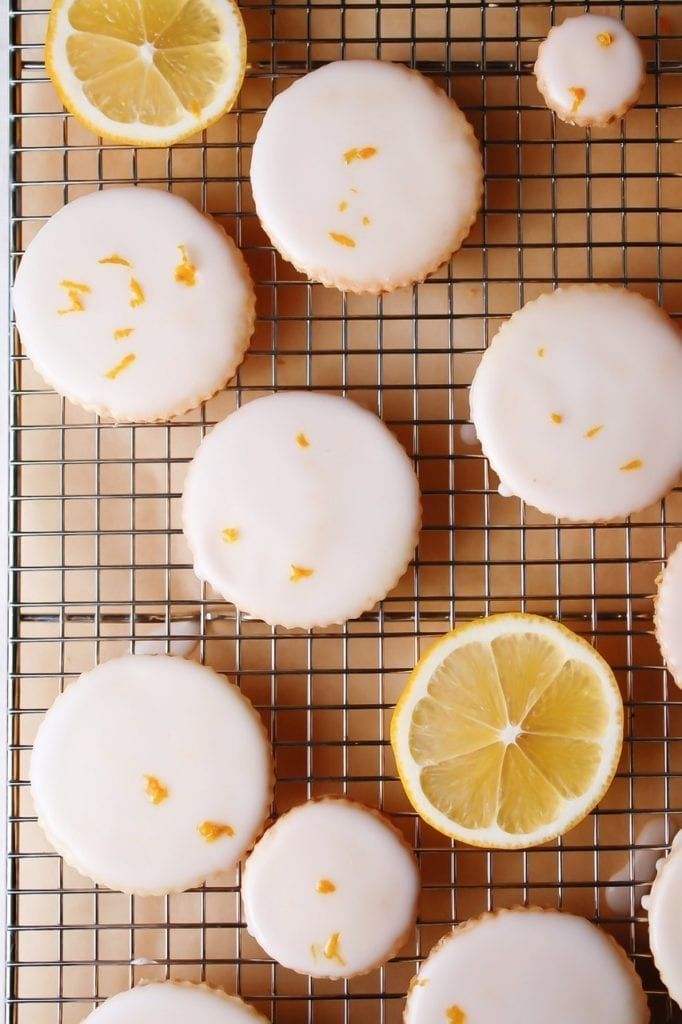 iced lemon cookies on a cooling rack with one cut in half and the other whole