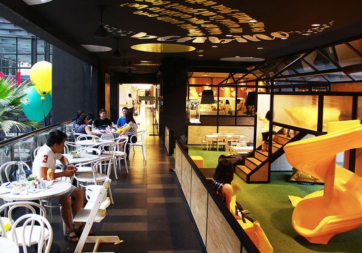 people sitting at tables in a restaurant with yellow and blue balloons hanging from the ceiling