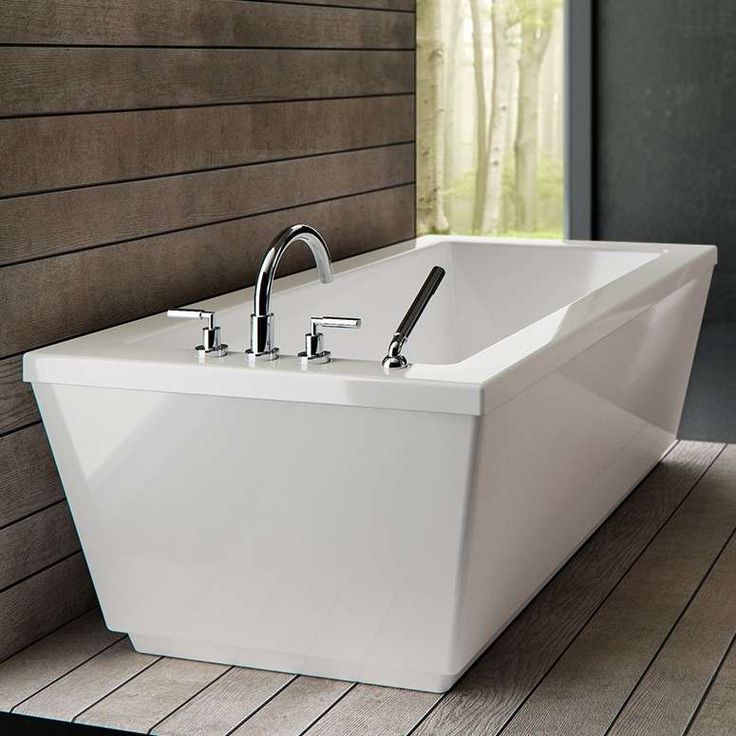 a large white bathtub sitting on top of a wooden floor next to a window