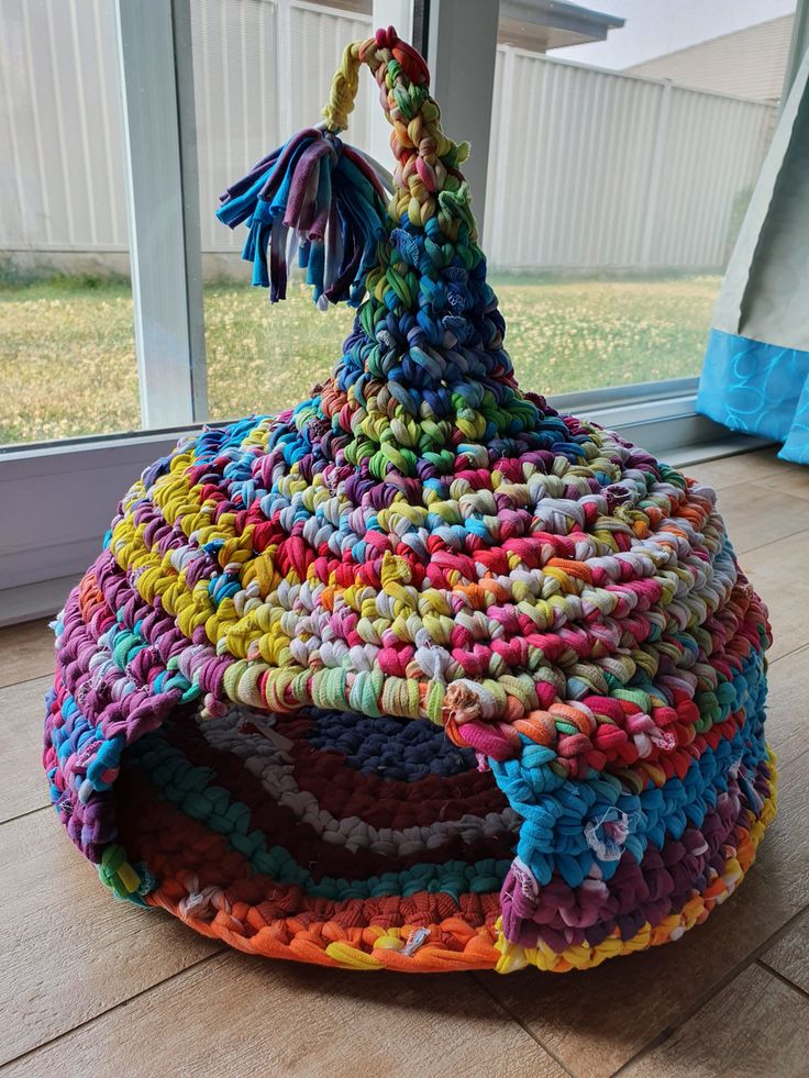 a multicolored basket sitting on the floor in front of a window