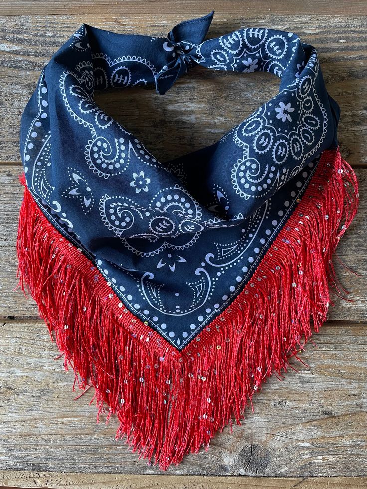 a bandana with red fringes and blue paisley print on the front, sitting on a wooden surface