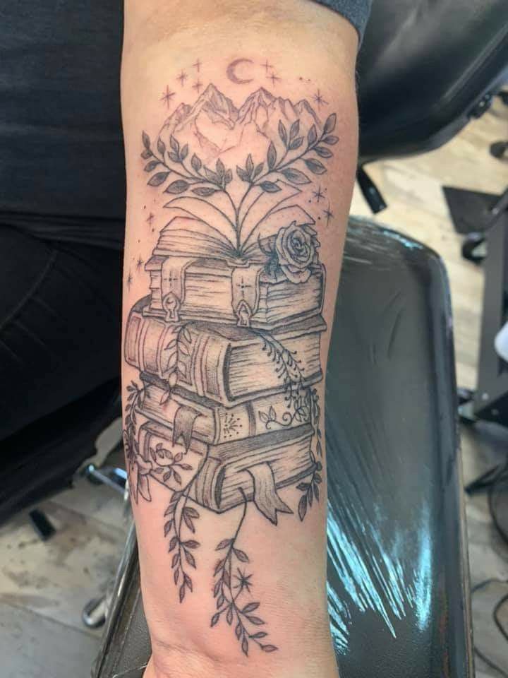 a person with a tattoo on their arm holding a stack of books and an arrow