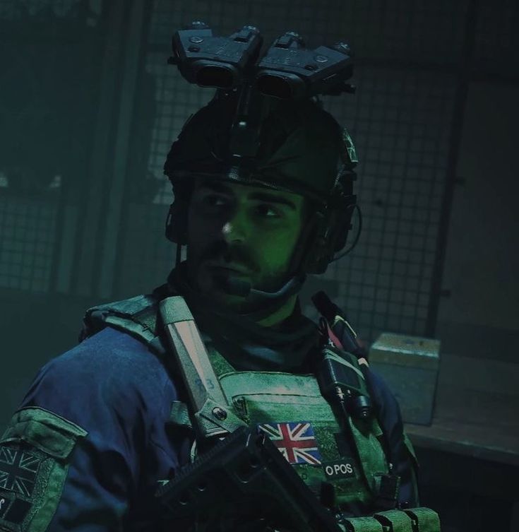 a man with a helmet and goggles standing in a dark room, looking at the camera