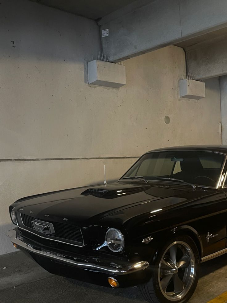 an old black mustang parked in a parking garage