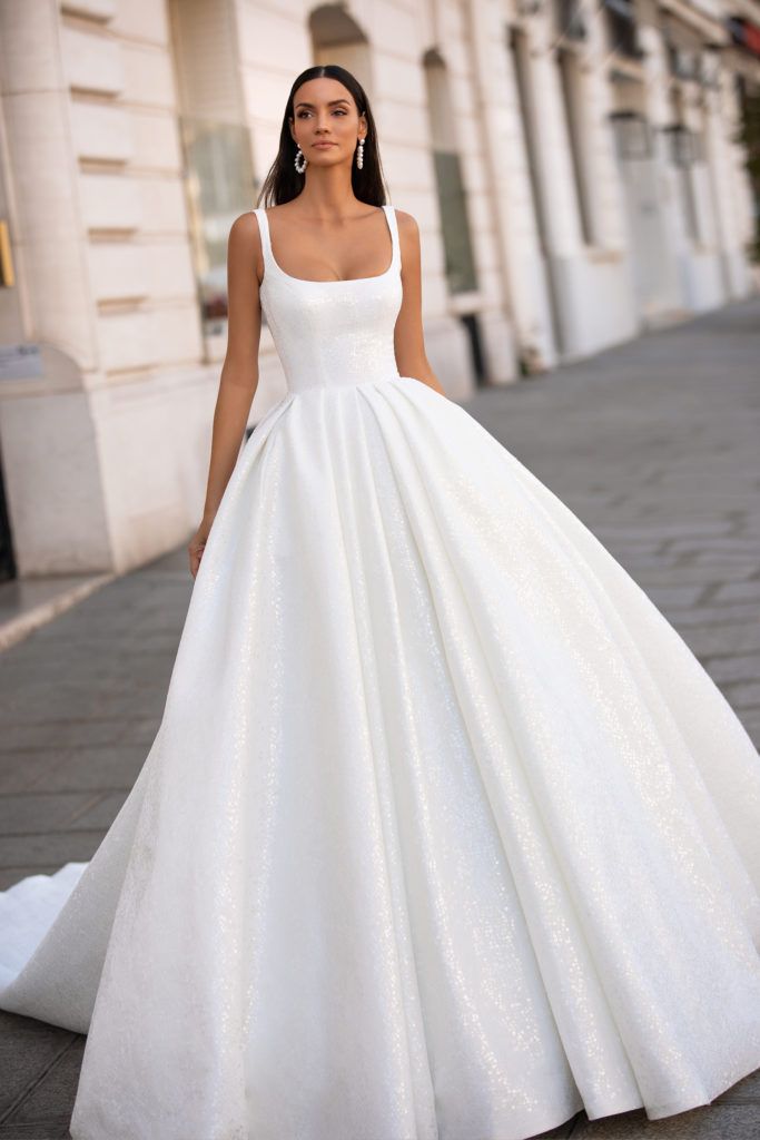 a woman in a white wedding dress standing on the street