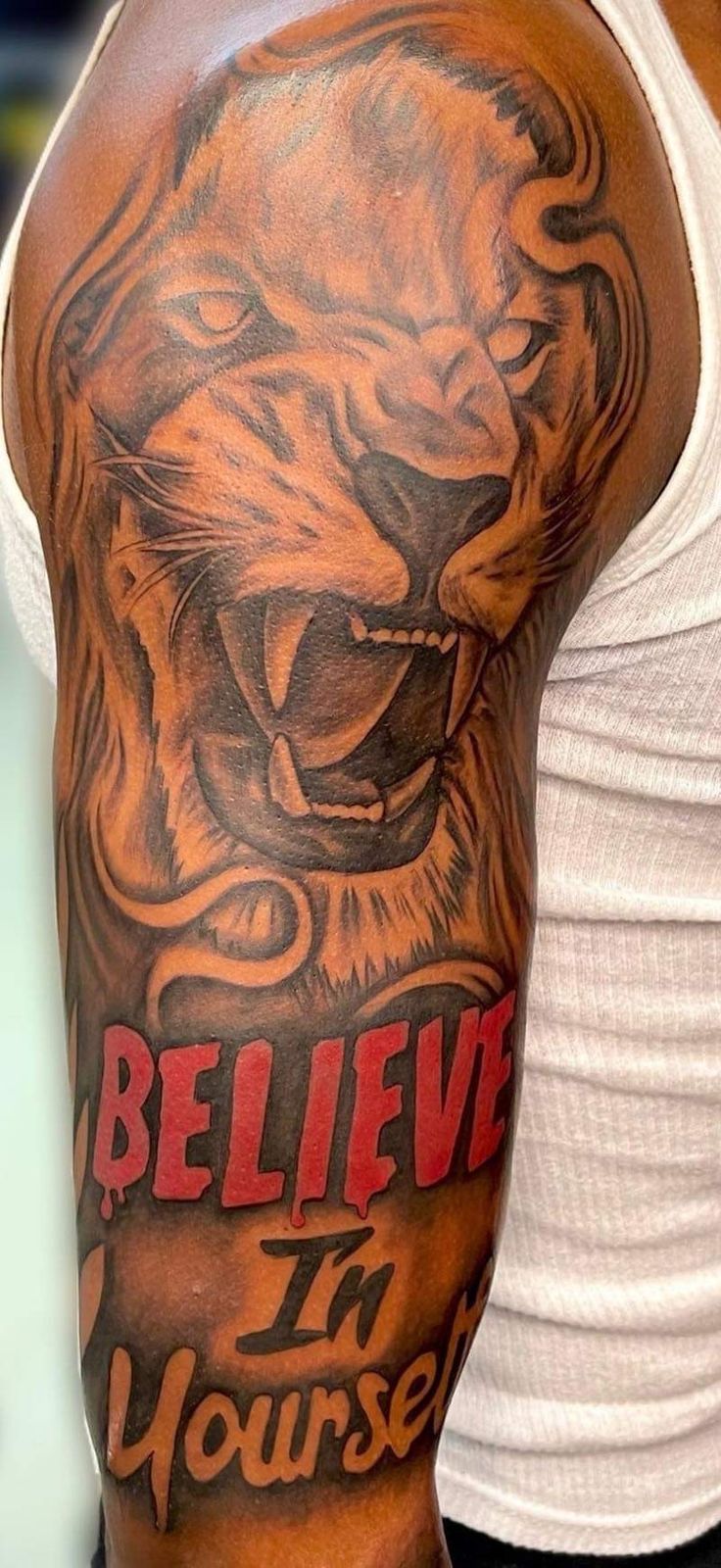 a man with a tattoo on his arm that says believe in yourself and an image of a lion