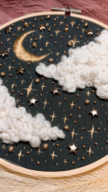 a close up of a cross stitch pattern with stars and clouds in the night sky