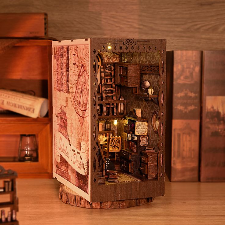 a wooden box with various items inside on a table next to other boxes and books