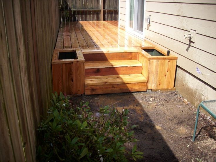 a wooden deck with steps leading up to the back door and side yard area next to it