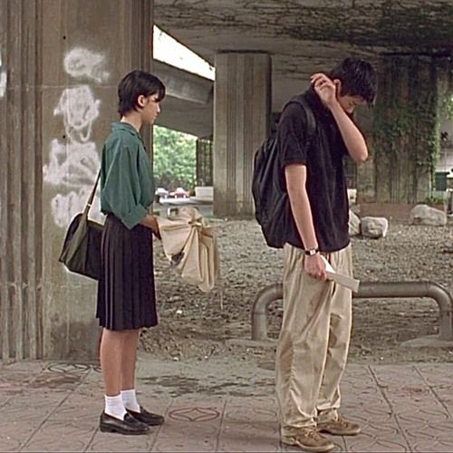 a man and woman standing next to each other talking on cell phones in front of an underpass