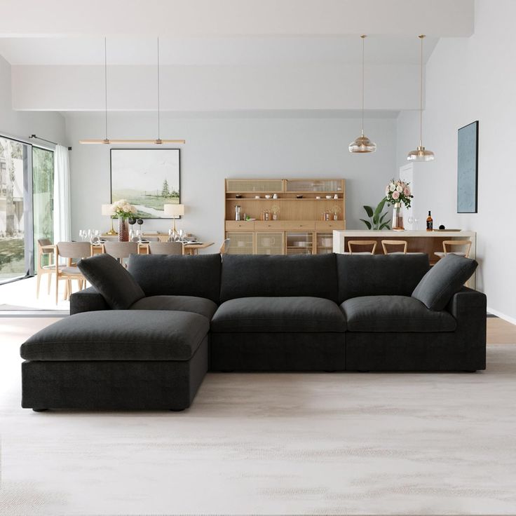 a living room with a large black couch in the center and dining table to the side