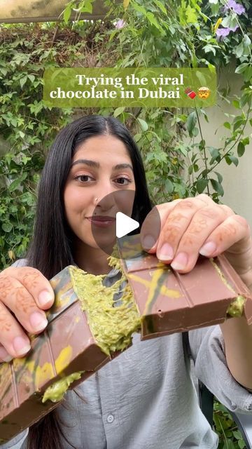 a woman holding a chocolate bar in her hands with the words trying the visual chocolate in dubai