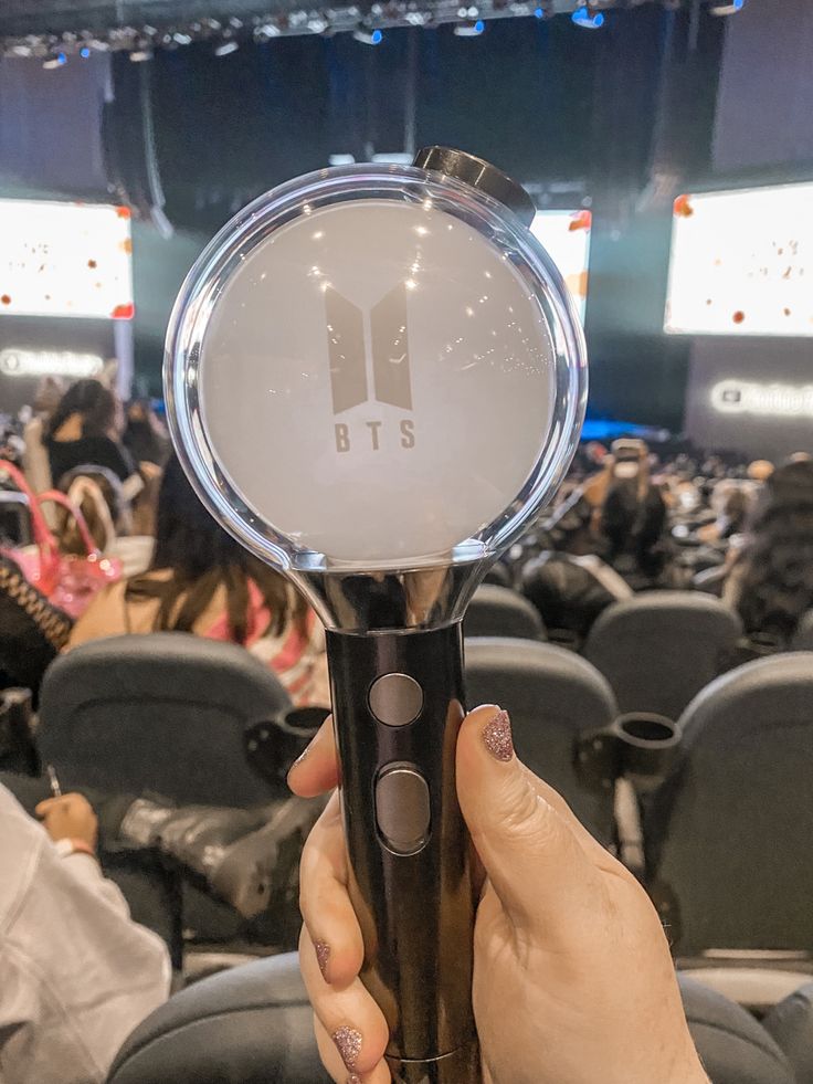 a person is holding up a microphone in front of an audience at a conference hall