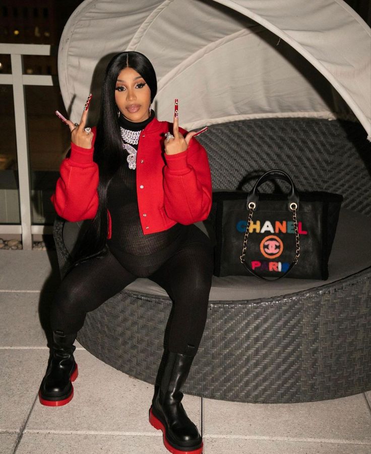 a woman with long black hair sitting on a bench holding two fingers up in the air