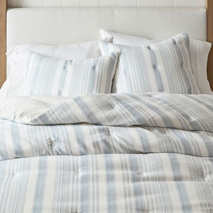 an unmade bed with blue and white striped sheets