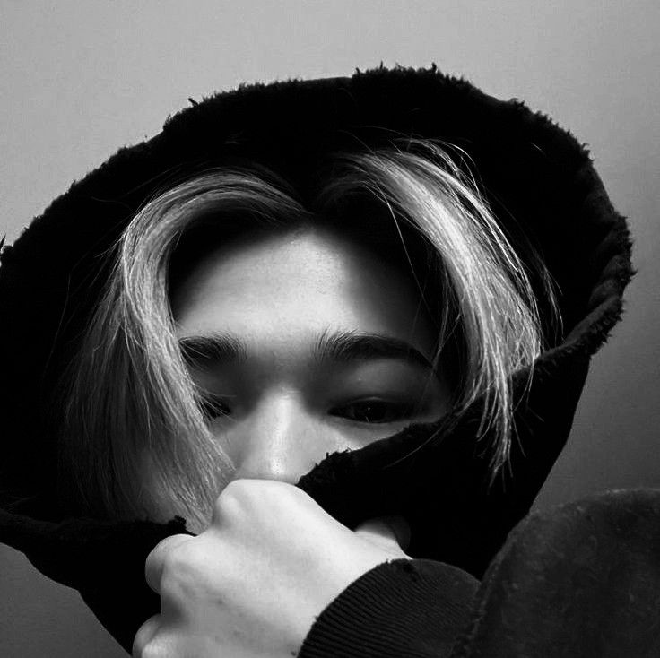 a woman with blonde hair wearing a black hoodie and holding her hands to her face