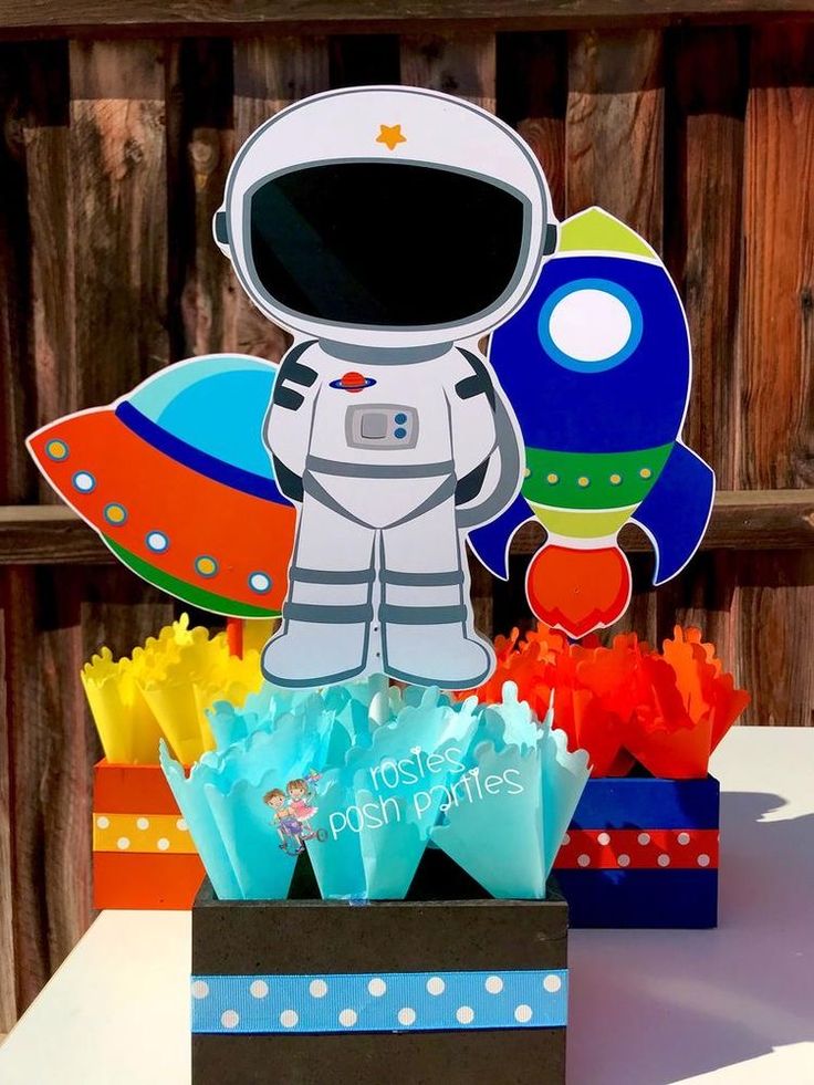 an astronaut themed centerpiece in a box on a table next to other paper decorations