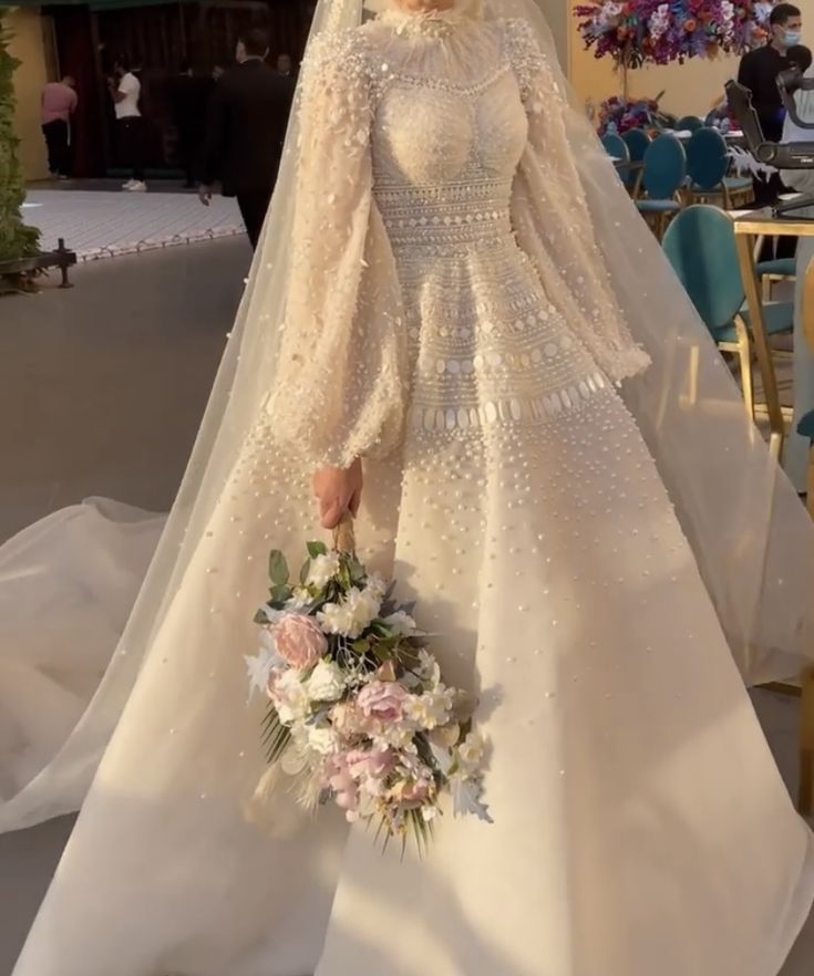 a wedding gown and veil on display in front of a table with chairs, tables and flowers