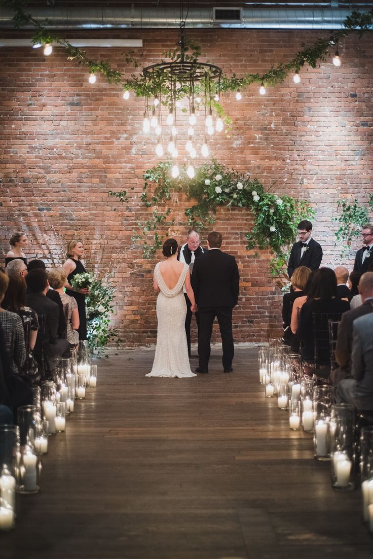 a bride and groom standing at the end of an aisle with candles in front of them