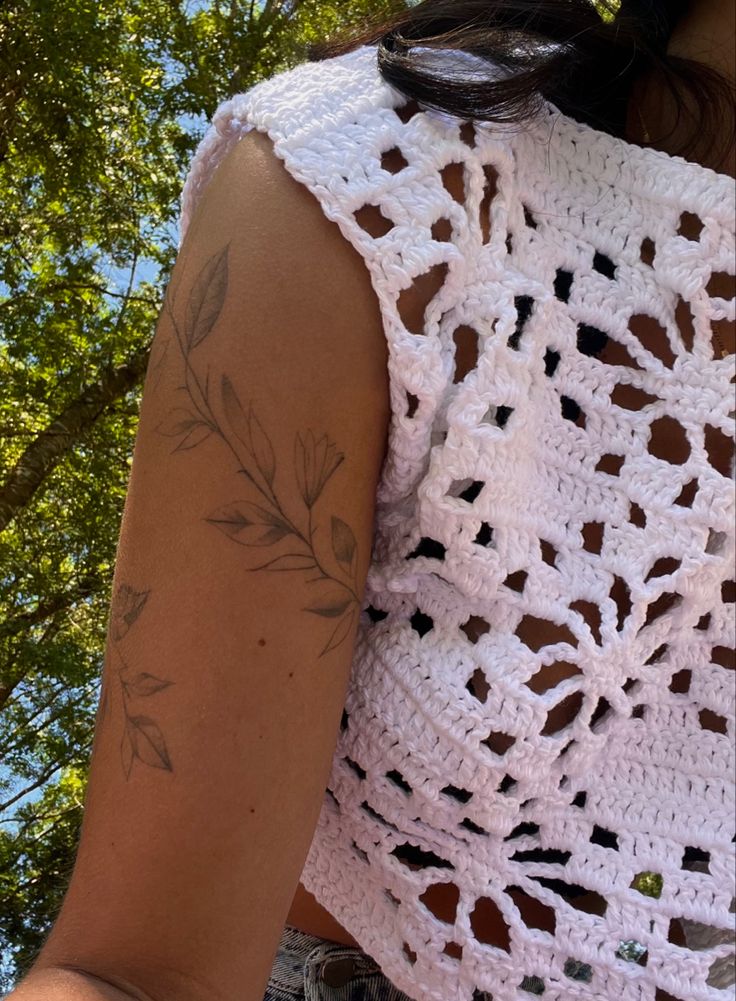 a woman wearing a white crochet top and holding a cell phone in her hand