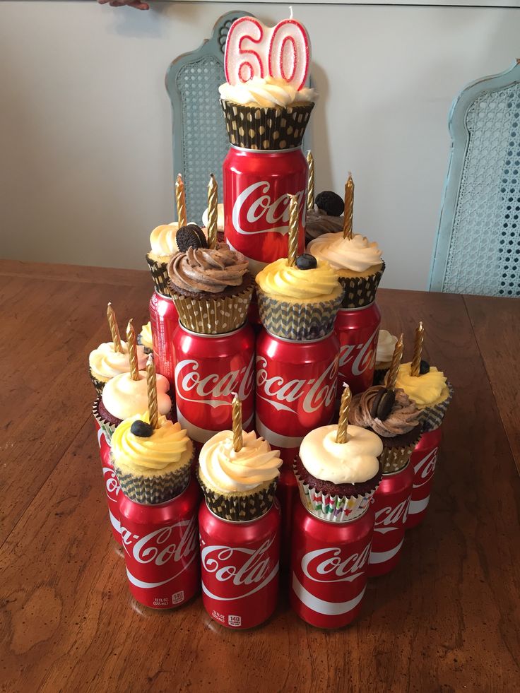 a stack of coca - cola cans with cupcakes on top