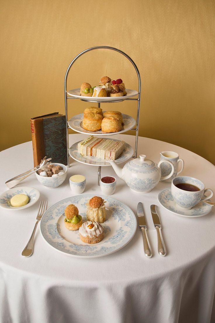 a white table topped with plates and cups filled with desserts next to a book