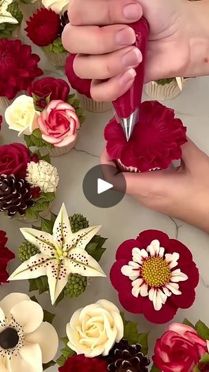 someone is cutting flowers out of cupcakes on a table with red and white frosting