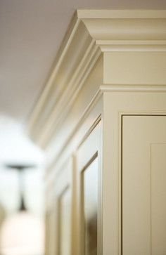 an empty hallway with white walls and wood trim on the door, in front of a lamp