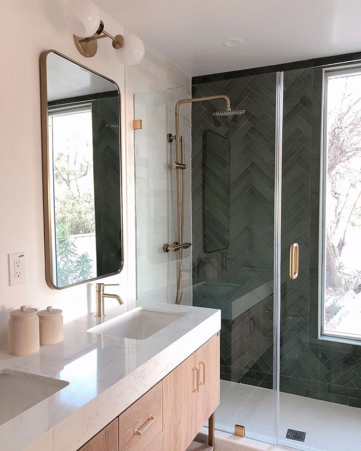 a bathroom with a walk in shower next to a double sink vanity and large mirror