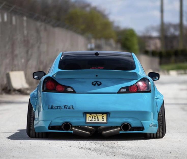 the back end of a blue car parked in front of a fenced off area