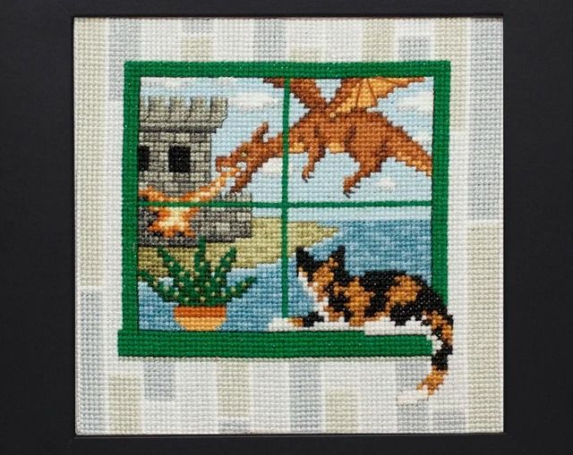 a cross stitch picture with a cat and bird looking out the window at the ocean