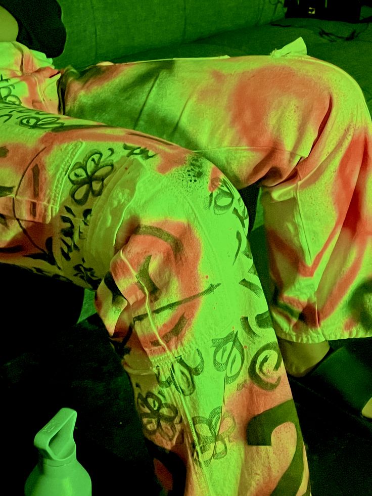 a person laying on the ground with their feet up in front of them, wearing green and pink pajamas