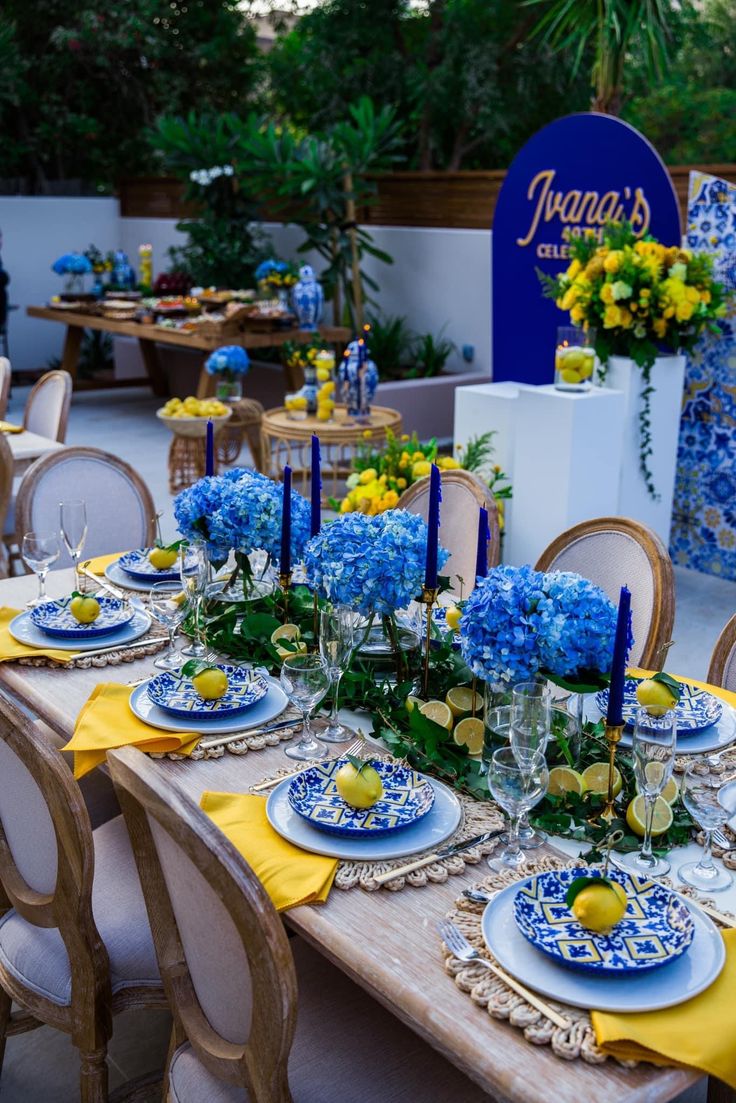 the table is set with blue and yellow plates, place settings, and centerpieces