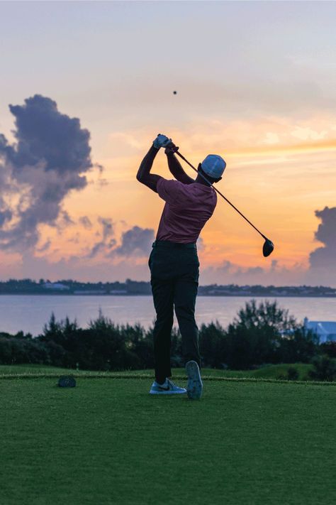 a man swinging his golf club at sunset on the green with clouds in the background