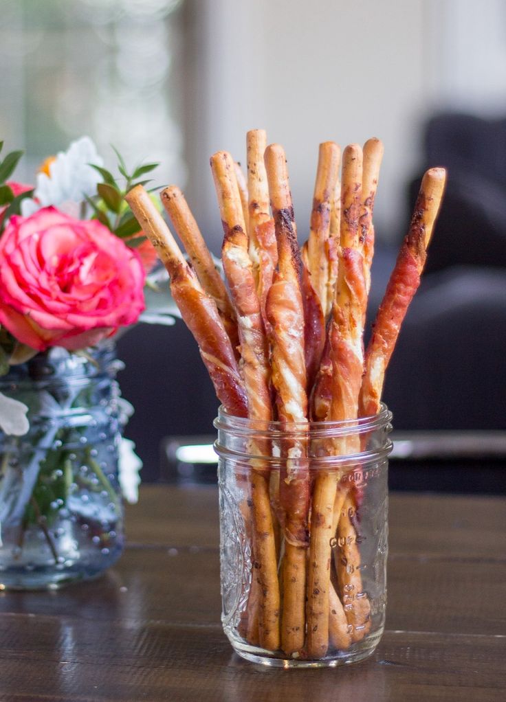 there are many different types of food in the glass jar on the table next to flowers