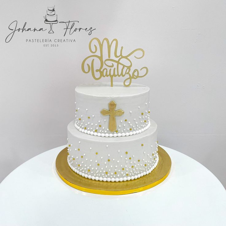 a white cake with gold lettering and a cross on top