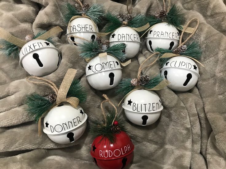 six ceramic ornaments with words and pine cones hanging from the top, on a blanket