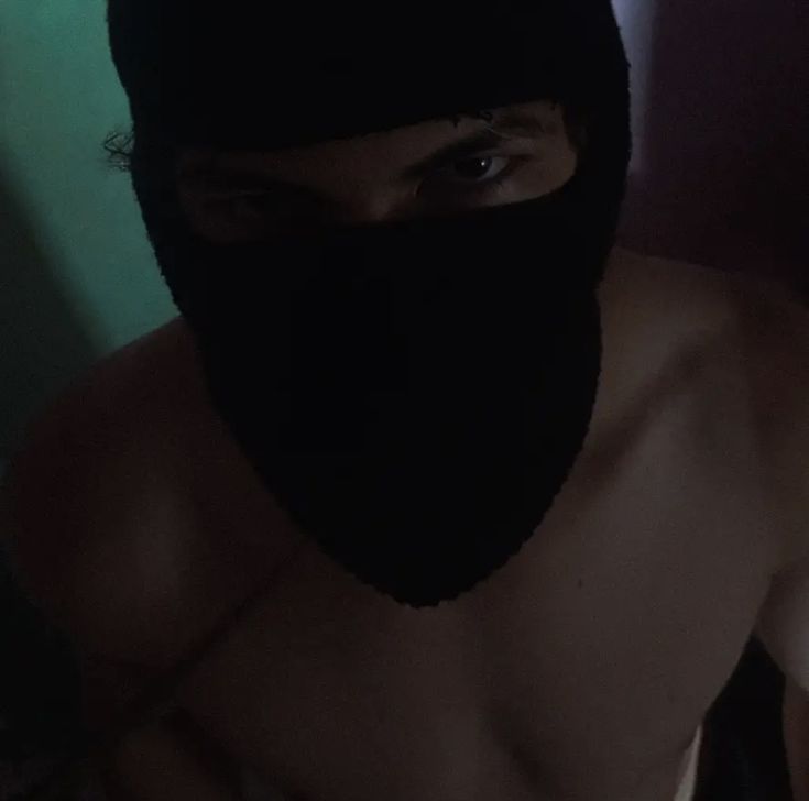 a shirtless man wearing a black mask and no shirt is looking at the camera