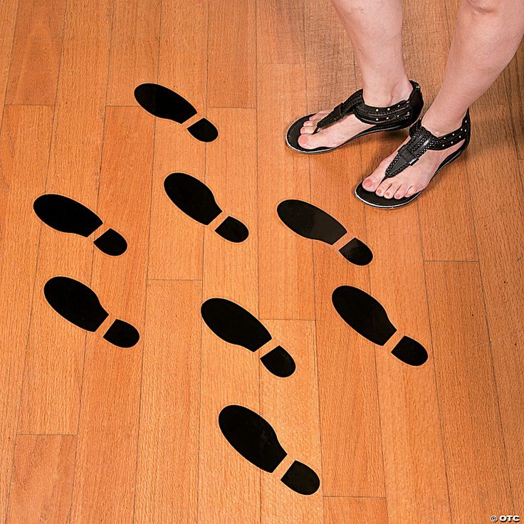 a person standing on a wooden floor with black footprints